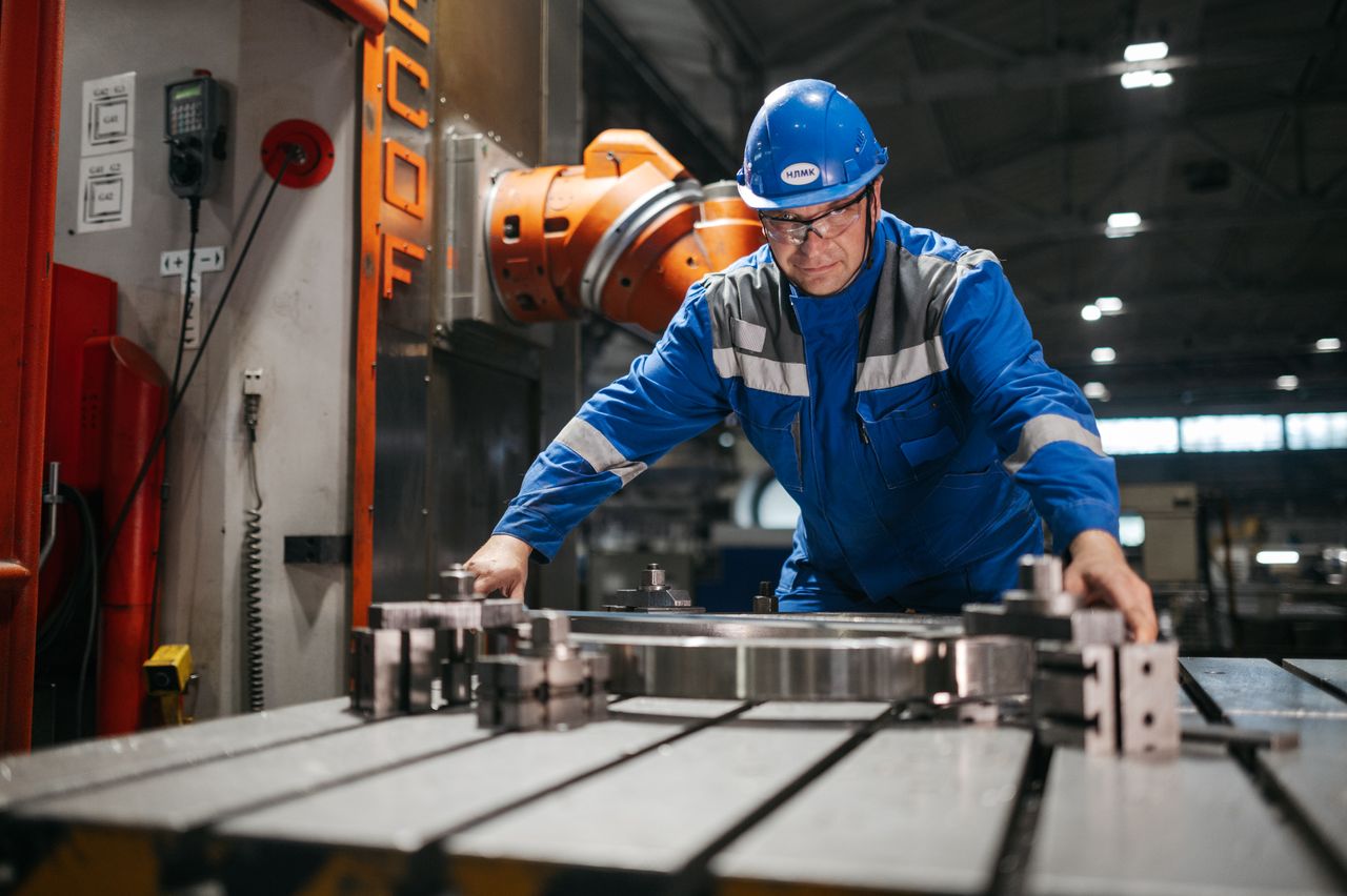 Home Male worker in blue uniform operates machinery in an industrial factory setting, showcasing engineering and industry.